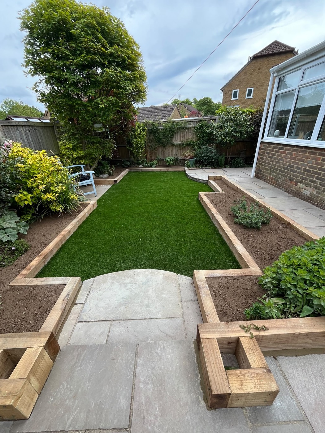A finished artificial-grass lawn with sleeper beds and patio
